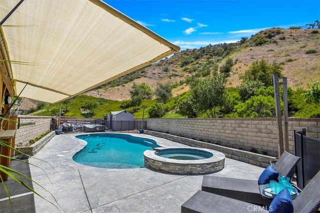 view of pool with a patio, a fenced backyard, a mountain view, and a pool with connected hot tub