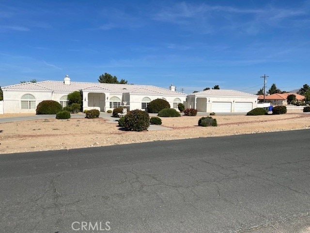 15360 Mandan Rd, Apple Valley, CA 92307 - view of front of house with an attached garage, a tile roof, driveway, a chimney, and stucco siding