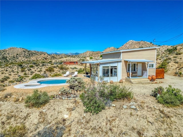 56714 Nelson Ave, Yucca Valley, CA 92284 - back of house with a mountain view, a sunroom, an outdoor pool, and covered porch