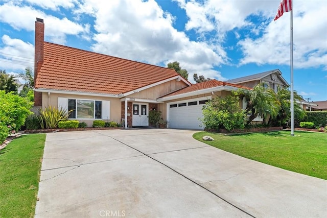 view of front of house with a tile roof, a chimney, driveway, an attached garage, and a front yard