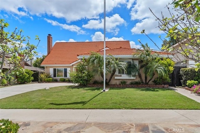 view of front of home with a tiled roof, a chimney, a front yard, and stucco siding