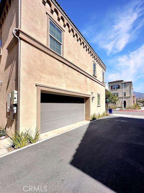 843 Cranberry Way, Upland, CA 91786 - view of side of property featuring stucco siding, an attached garage, and asphalt driveway