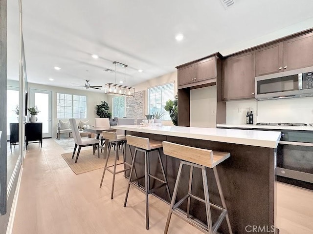 843 Cranberry Way, Upland, CA 91786 - kitchen with stainless steel microwave, plenty of natural light, dark brown cabinetry, recessed lighting, and light wood-type flooring