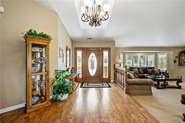 foyer entrance with baseboards, wood finished floors, and a chandelier