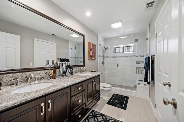 full bathroom featuring a shower stall, double vanity, and toilet