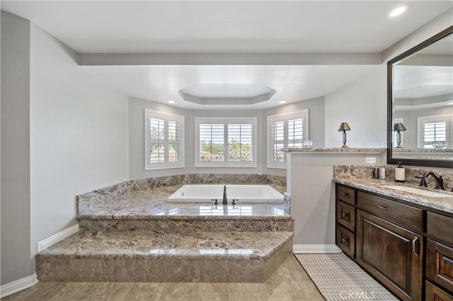 bathroom with a bath, baseboards, vanity, a tray ceiling, and recessed lighting