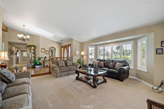 living area with healthy amount of natural light, a chandelier, baseboards, a skylight, and vaulted ceiling