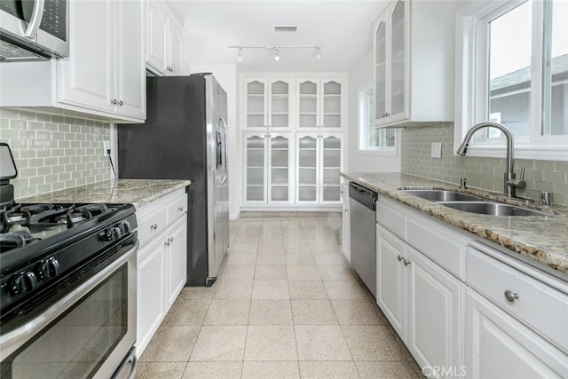 7857 Whitsett Ave, North Hollywood, CA 91605 - kitchen featuring stainless steel appliances, a sink, white cabinetry, glass insert cabinets, and light stone countertops