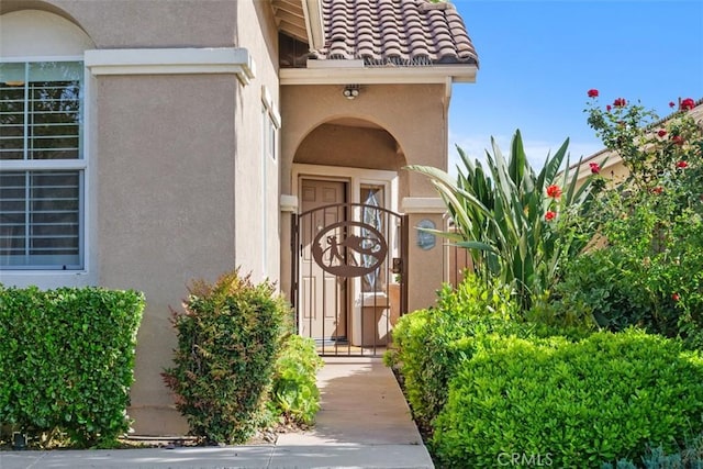 28399 Long Meadow Dr, Menifee, CA 92584 - view of exterior entry featuring stucco siding, a gate, and a tiled roof