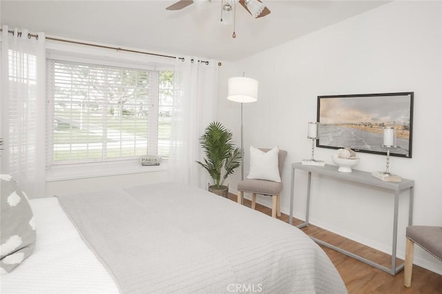 bedroom with wood finished floors, multiple windows, baseboards, and ceiling fan