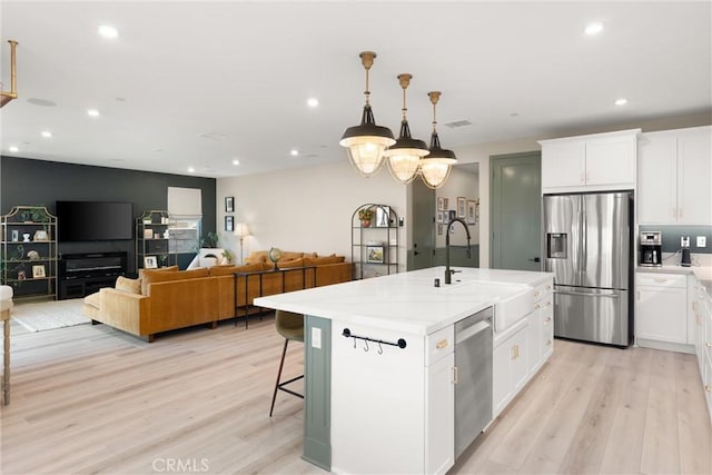 920 Bunkhouse Dr, Rancho Mission Viejo, CA 92694 - kitchen with stainless steel appliances, light wood-style floors, recessed lighting, an island with sink, and white cabinetry