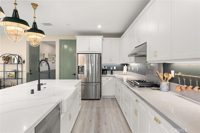 920 Bunkhouse Dr, Rancho Mission Viejo, CA 92694 - kitchen with appliances with stainless steel finishes, light wood-type flooring, range hood, white cabinets, and hanging light fixtures