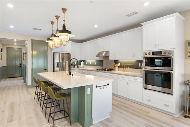 920 Bunkhouse Dr, Rancho Mission Viejo, CA 92694 - kitchen with appliances with stainless steel finishes, light wood finished floors, light countertops, a center island with sink, and recessed lighting