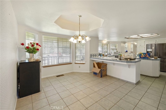 50711 Rd 426, Oakhurst, CA 93644 - kitchen featuring stainless steel refrigerator with ice dispenser, tile counters, a peninsula, a chandelier, and light tile patterned flooring