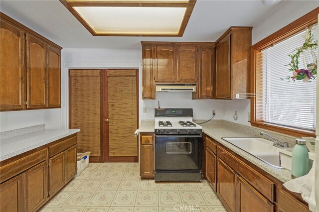 50711 Rd 426, Oakhurst, CA 93644 - kitchen with gas range oven, under cabinet range hood, a sink, light countertops, and brown cabinetry