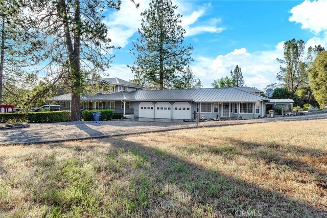 50711 Rd 426, Oakhurst, CA 93644 - view of front of home featuring an attached garage, asphalt driveway, a metal roof, and a front lawn