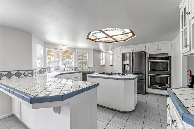 50711 Rd 426, Oakhurst, CA 93644 - kitchen featuring stainless steel appliances, tile countertops, a peninsula, a center island, and a textured ceiling