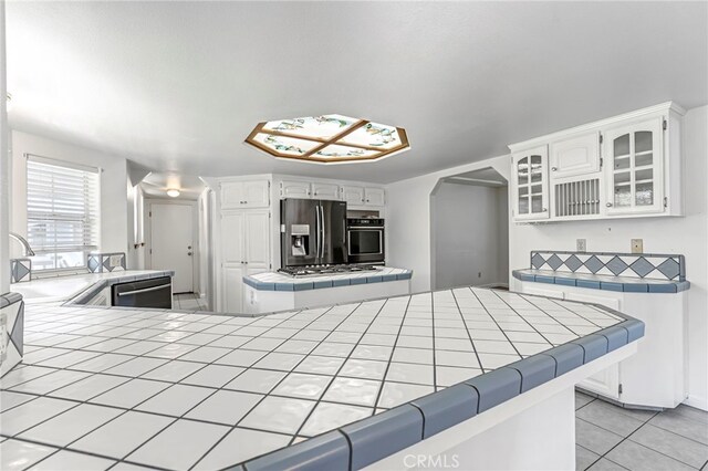 50711 Rd 426, Oakhurst, CA 93644 - kitchen featuring stainless steel appliances, tile countertops, light tile patterned flooring, and glass insert cabinets