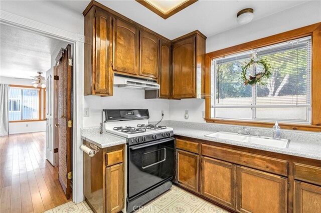 50711 Rd 426, Oakhurst, CA 93644 - kitchen featuring gas range oven, under cabinet range hood, light countertops, brown cabinetry, and light wood finished floors