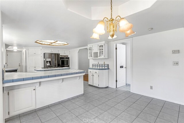 50711 Rd 426, Oakhurst, CA 93644 - kitchen featuring stainless steel appliances, tile counters, white cabinets, and a chandelier