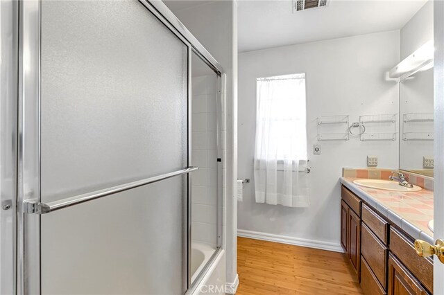 50711 Rd 426, Oakhurst, CA 93644 - bathroom with double vanity, wood finished floors, and bath / shower combo with glass door