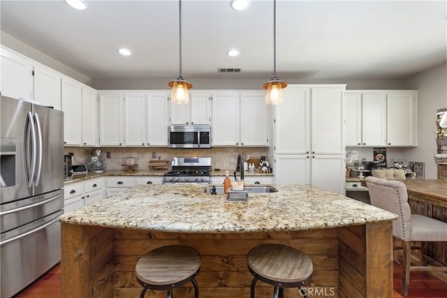 28759 Eridanus Dr, Menifee, CA 92586 - kitchen featuring stainless steel appliances, a sink, white cabinets, a kitchen breakfast bar, and an island with sink
