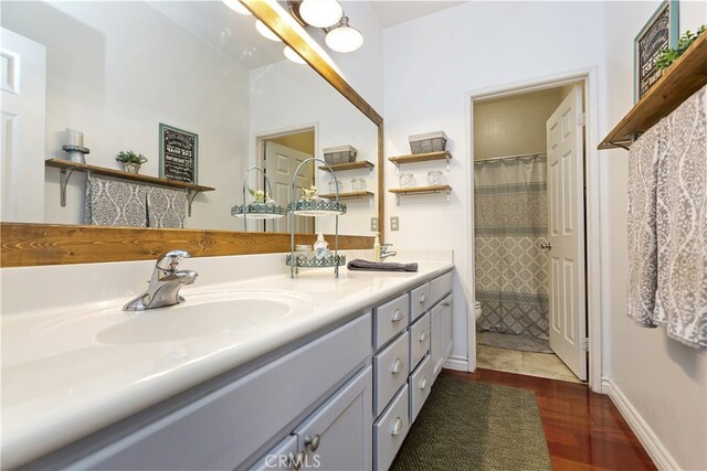 28759 Eridanus Dr, Menifee, CA 92586 - bathroom featuring toilet, double vanity, wood finished floors, a shower with curtain, and baseboards