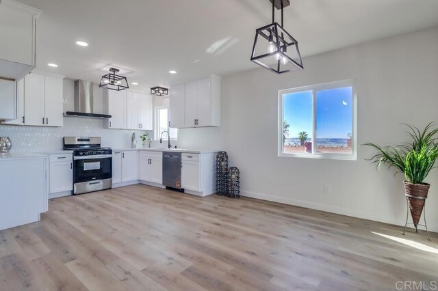 1215 Grand Ave, Spring Valley, CA 91977 - kitchen with appliances with stainless steel finishes, wall chimney exhaust hood, light wood finished floors, white cabinets, and recessed lighting