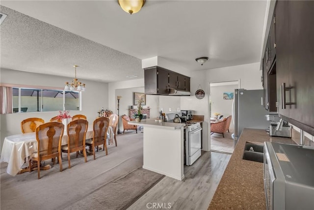 1487 Asbury Dr, Pasadena, CA 91104 - kitchen with white range with gas stovetop, under cabinet range hood, a chandelier, light wood-style floors, and a peninsula