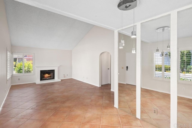unfurnished living room featuring light tile patterned floors, lofted ceiling, a lit fireplace, and baseboards