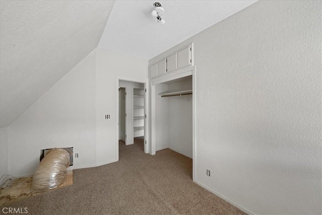 unfurnished bedroom featuring light colored carpet, vaulted ceiling, and a closet