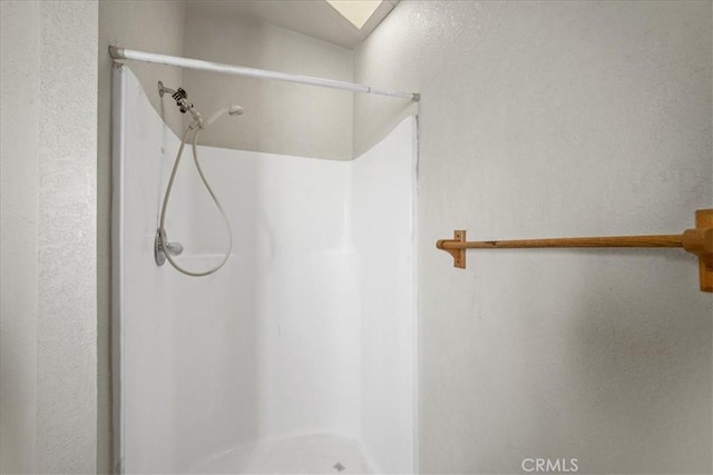 bathroom featuring a stall shower and a textured wall