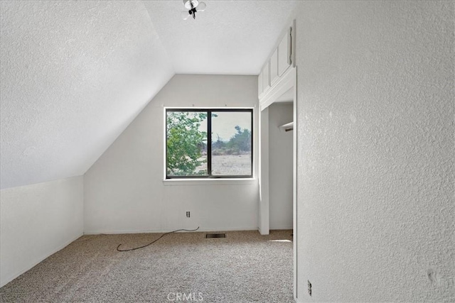 bonus room featuring a textured ceiling, vaulted ceiling, carpet flooring, and a textured wall
