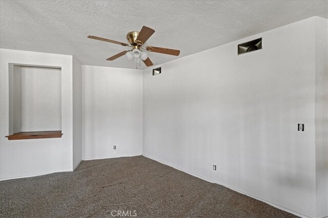 unfurnished room with a ceiling fan, dark colored carpet, and a textured ceiling