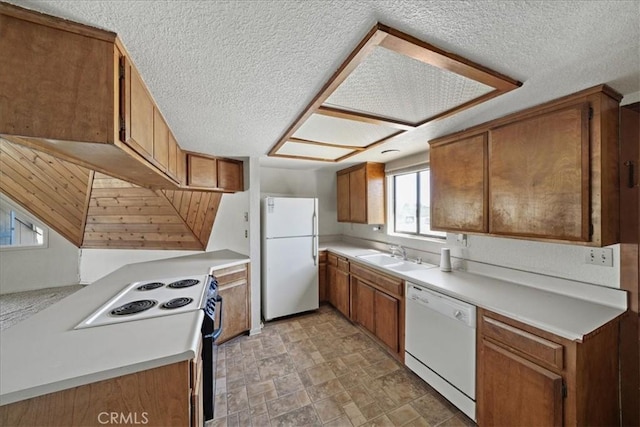 kitchen featuring white appliances, a sink, brown cabinetry, light countertops, and a textured ceiling