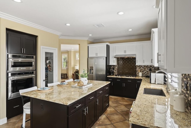 6407 Calmeria Pl, Carlsbad, CA 92011 - kitchen featuring appliances with stainless steel finishes, under cabinet range hood, a sink, a kitchen island, and white cabinetry