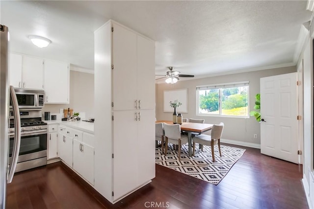 5573 Kiowa Dr, La Mesa, CA 91942 - kitchen featuring stainless steel appliances, dark wood-style floors, a ceiling fan, white cabinetry, and crown molding