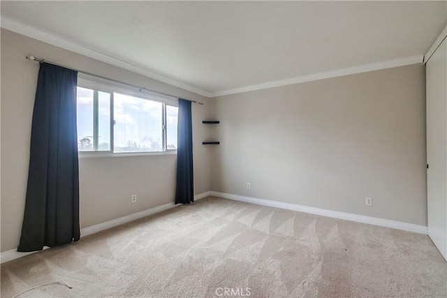 empty room with ornamental molding, light carpet, and baseboards