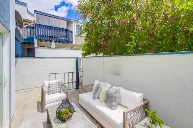 view of patio / terrace featuring a balcony, an outdoor living space, and fence