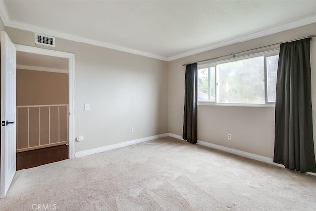 empty room featuring carpet floors, crown molding, and baseboards