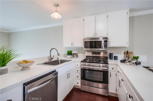 kitchen with appliances with stainless steel finishes, a sink, ornamental molding, light countertops, and white cabinets