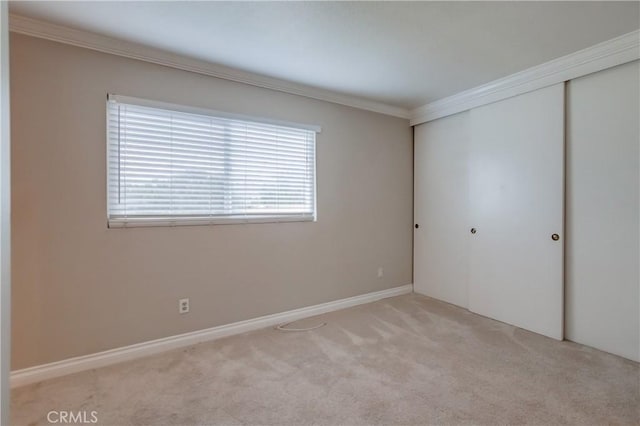 unfurnished bedroom featuring crown molding, a closet, carpet, and baseboards