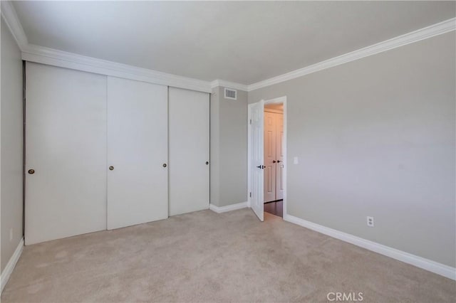 unfurnished bedroom with carpet flooring, ornamental molding, a closet, and baseboards