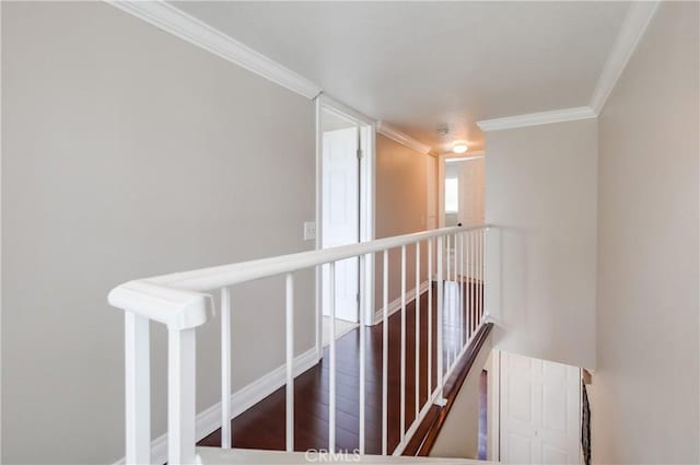 hallway featuring an upstairs landing, crown molding, wood finished floors, and baseboards