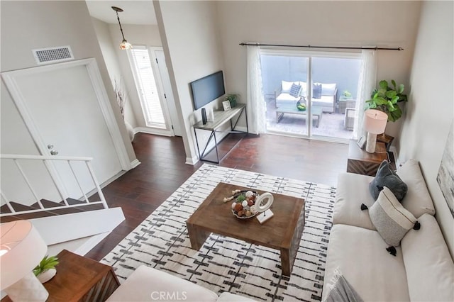living area featuring dark wood-style floors, a towering ceiling, and baseboards