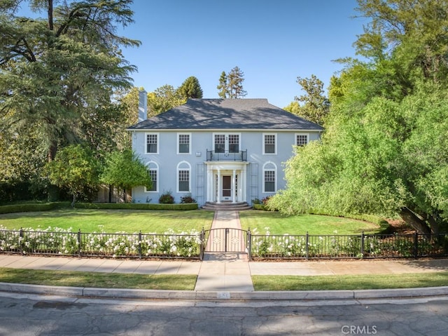 605 E Home Ave, Fresno, CA 93728 - colonial house with a gate, a balcony, stucco siding, and a chimney