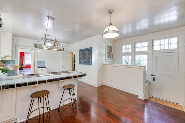 605 E Home Ave, Fresno, CA 93728 - kitchen featuring tile countertops, dark wood-style floors, baseboards, and a breakfast bar