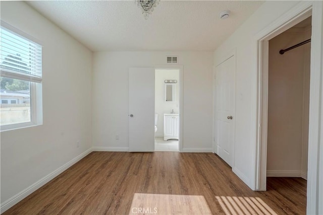 1517 W Romneya Dr, Anaheim, CA 92801 - unfurnished bedroom featuring wood finished floors, baseboards, a textured ceiling, and connected bathroom