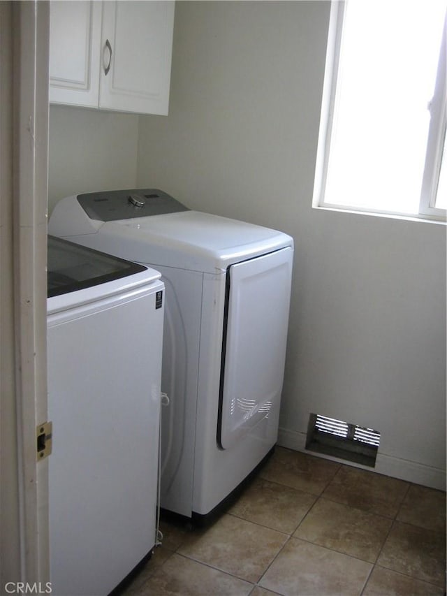 laundry area with cabinet space, washer and dryer, light tile patterned floors, and baseboards