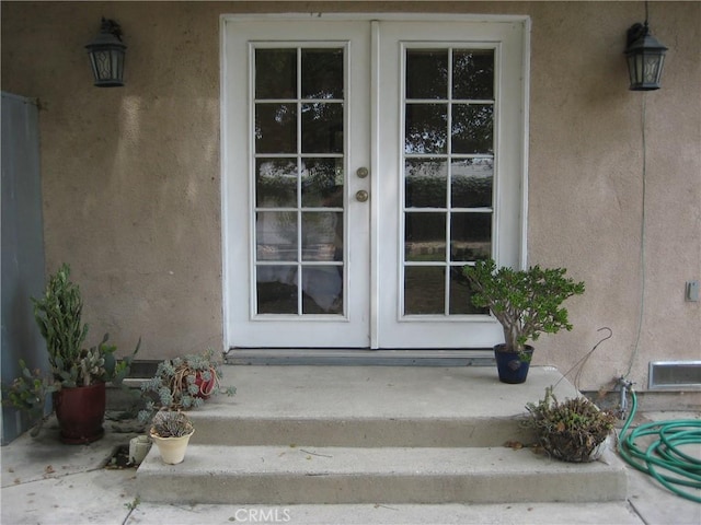 view of exterior entry featuring french doors and stucco siding